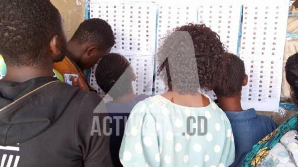 electeurs-en-train-de-consulter-des-listes-dans-un-bureau-de-vote.jpeg